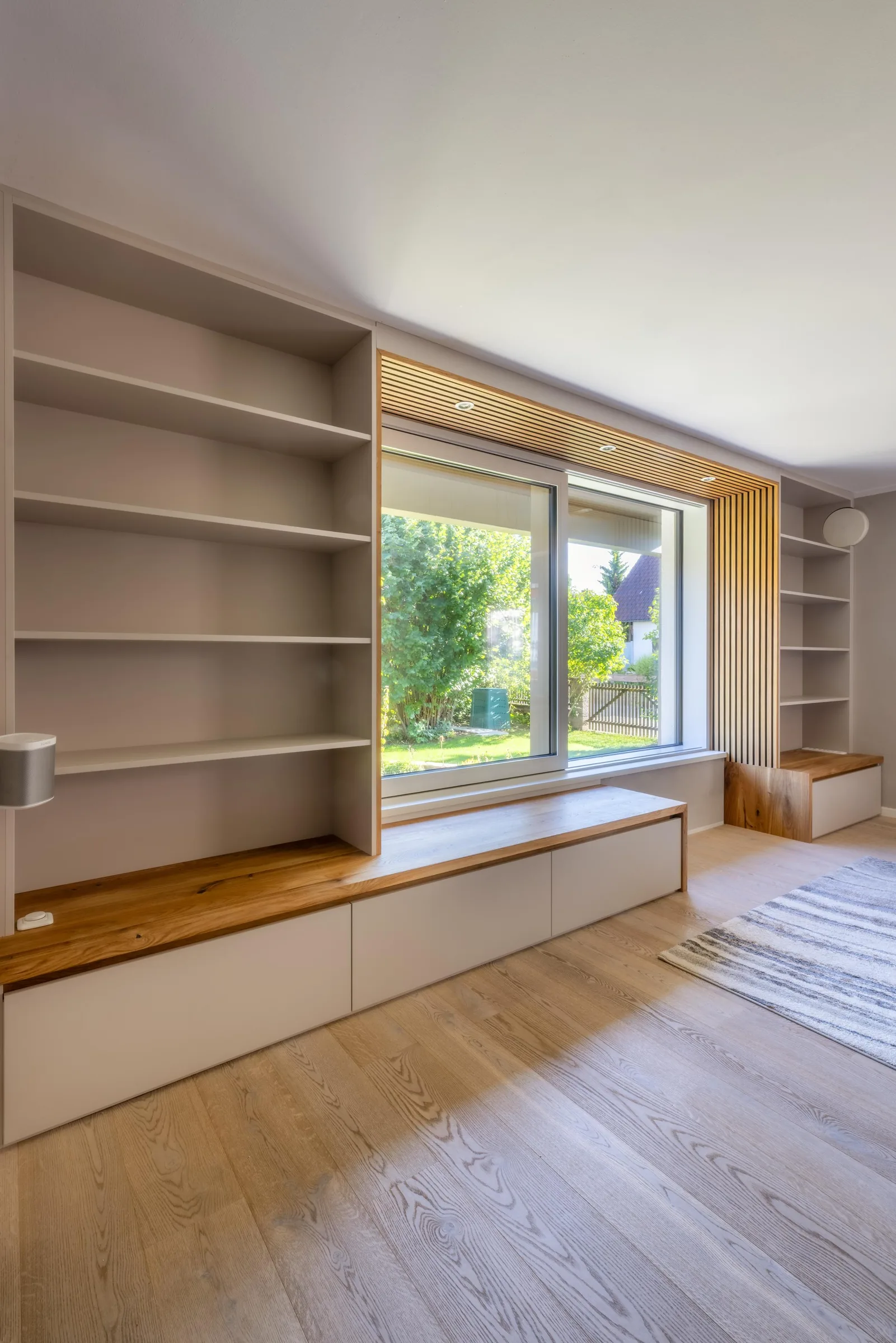Individuell ausgebaute Wohnwand mit Sitzbank, Regalen und Holzlamellen